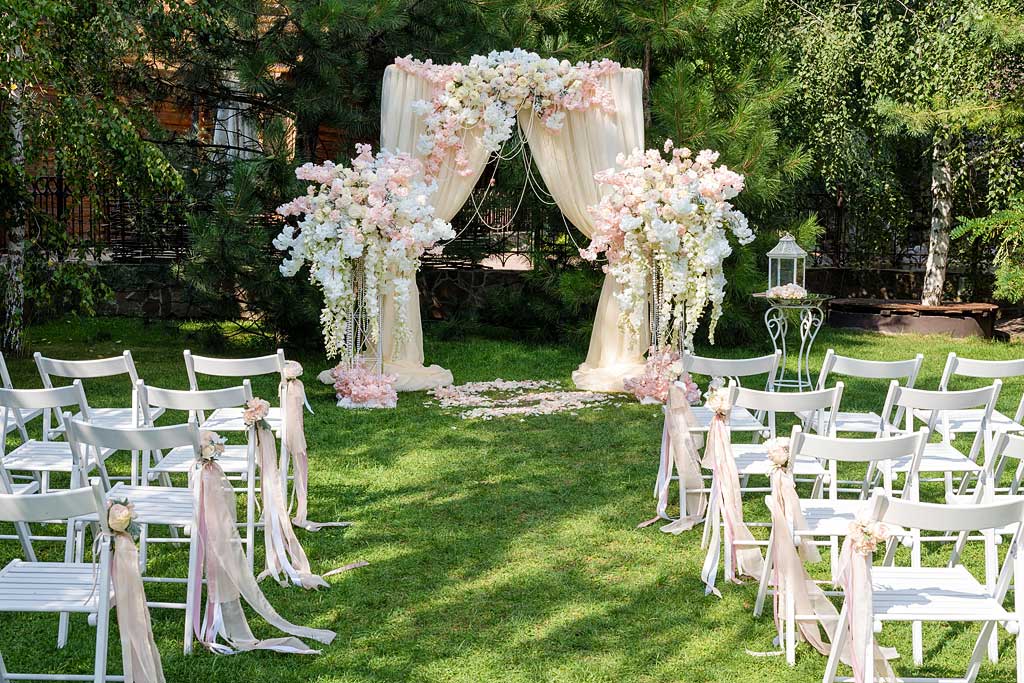 Scaune pliante de nuntă pregătite pentru o ceremonie în grădină