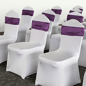 białe pokrowce na krzesła bankietowe i purpurowe wstęgi ozdobne